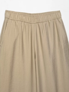 Detail of high-waist elastic waistband and side pockets on khaki wide-leg pants