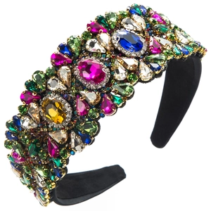 Close-up of vibrant colorful rhinestones and emerald crystals on a black velvet headband