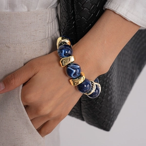 Dettaglio delle perle in acrilico marmorizzato blu e pezzi in metallo dorato sul bracciale