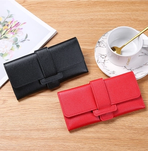 Detailed view of trifold leather long wallets in black and red on a wooden desk