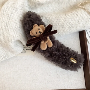 Detail of plush brown hair claw clip with bear decor and velvet bow on knit background