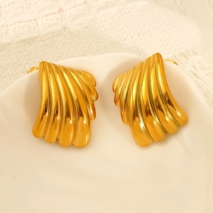 Élégantes boucles d'oreilles dorées en forme d'éventail sur un plat en céramique
