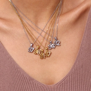 Close-up of layered 18K gold and silver year necklaces with micro-pave zircons