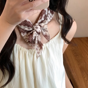 Close-up of lightweight brown and beige silk scarf with geometric diamond patterns