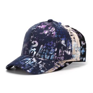 Detail of three printed baseball caps in navy, beige and black with artistic M logo