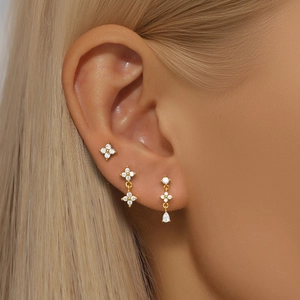 Macro detail of three-piece gold earring set with zircon kite-shaped floral designs