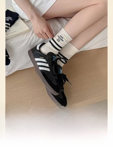 Close-up of striped white mid-tube socks with black embroidery styled with samba sneakers