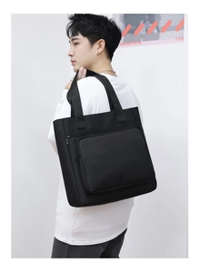 Side view of a black waterproof nylon tote bag worn by a model for business casual use