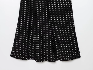 Close-up of black and white polka dot print with a wavy hem on a lightweight fabric dress