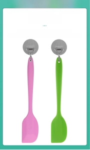 Detail of pink and green silicone spatulas hanging on hooks for easy storage