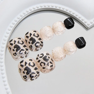 Champagne glitter and leopard print press-on toenails on a white decorative mirror