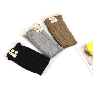 Detail of cable knit leg warmers with lace trim and wooden buttons in black, gray, and brown