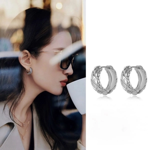 Detailed view of silver hoop earrings with diamond pattern texture on a female model