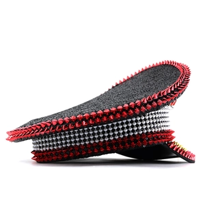 Detail of red punk spikes and white pearl beads on a black sequined captain hat