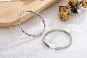 Close-up of large silver stainless steel hoop earrings with sparkling rhinestones