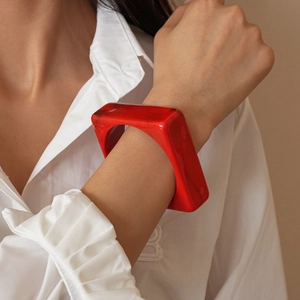 Close-up of a bold red geometric acrylic bangle with a marbled texture on a model's wrist