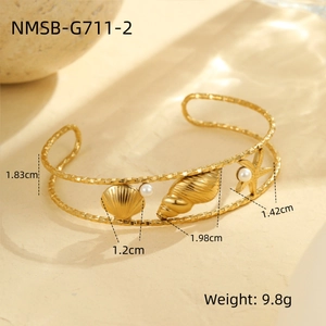 Detailed view of ocean theme gold bangle featuring starfish shell and pearl charms
