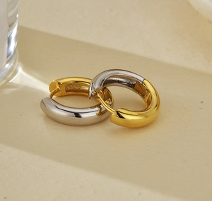 Macro shot of minimalist two-tone gold and silver circular hoop earrings with polished finish