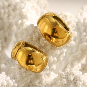 Macro di mini clip per orecchie a forma di C placcate oro 18K su sfondo di corallo bianco