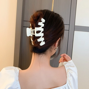 Détail d'une grande pince à cheveux géométrique blanche sur les cheveux du modèle