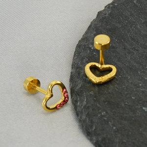 Macro shot of gold heart-shaped earrings featuring a sparkling pink gemstone detail