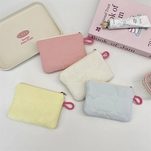 Detailed view of quilted cloud coin pouches in four pastel colors with metal zippers