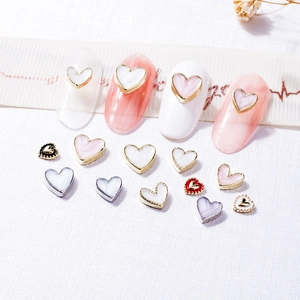 Assorted heart nail charms with gold and silver metal borders on white background