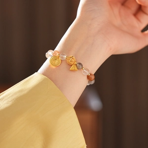 Detail of beaded bracelet featuring moonstone, crystal, and golden Fu pendant charms