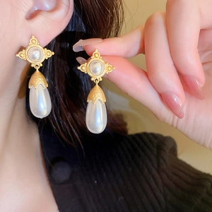 Boucles d'oreilles vintage dorées avec perles gouttes portées pour un style rétro chic