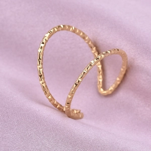 Macro shot of rose gold double-row cuff ring with geometric diamond-cut textures