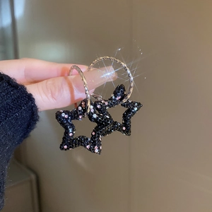 Gros plan de boucles d'oreilles étoiles noires avec strass et effet scintillant à la main