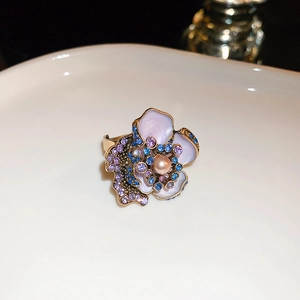 Detailed shot of golden ring with lavender petals, rhinestones and center pearl