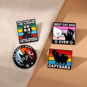 Cartoon enamel pins set featuring black cats and capybara badges on beige fabric texture