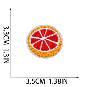 Detailed size view of fruit embroidery patch with orange and red fabric texture