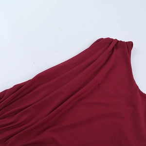 Détail d'une robe de soirée bordeaux à épaule dénudée montrant la texture plissée