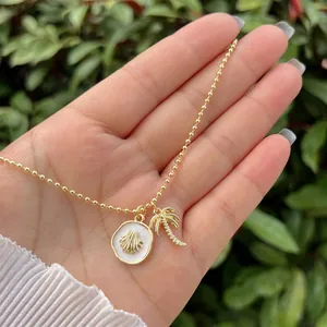 Detail of 18K gold beaded chain with shell and palm tree pendants in resort style