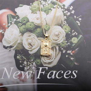 Close-up of gold lock and key pendant with clear zircons on a textured metal surface