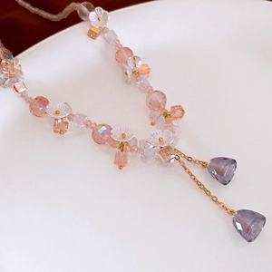 Detail of pink crystal beaded earring with flower charms and purple teardrop tassels