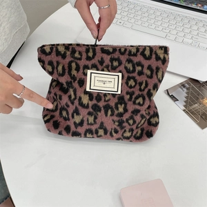 Close-up of leopard print plush cosmetic bag with PLEASANT TIME label and zipper detail