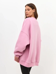 Detail view of the pink oversized fleece sweatshirt showing side-back fit and fabric drape