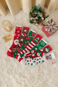 Flachbild von sechs Paar festlichen Weihnachts-Korallenvlies-Socken auf weißem Pelzteppich
