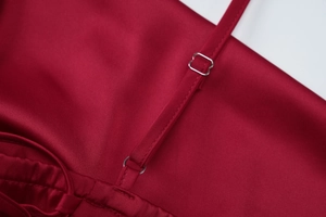 Detail of adjustable metal buckle and dark red satin strap on an elegant evening gown