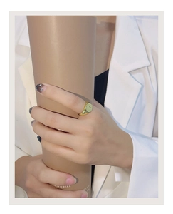 Detail of a geometric gold star ring worn on finger, featuring a circular signet design