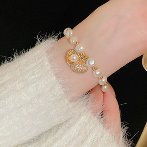 Detail view of a zircon shell and pearl adjustable bracelet on a model's wrist