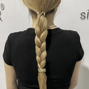 Detail of golden geometric hair clip and ring clasp on a braided ponytail hairstyle