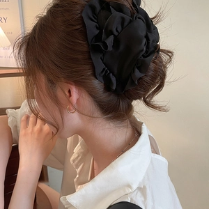 Elegant black pleated chiffon flower hair claw clip worn by a model in a soft setting