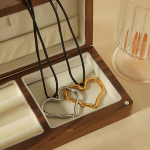 Detailed close-up of hollow heart-shaped gold and silver pendants in a wooden jewelry box