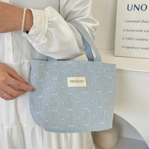 Gros plan d'un sac à main en denim bleu clair avec imprimé nœud blanc et étiquette