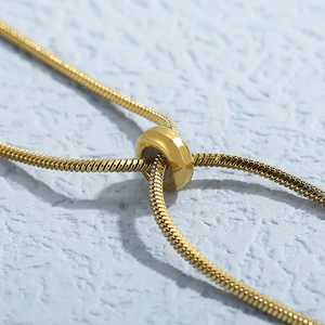 Golden snake chain necklace with adjustable slider clasp on blue textured background