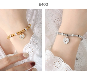 Detail of elegant gold and silver beaded bracelets with crystal-encrusted heart lock charm